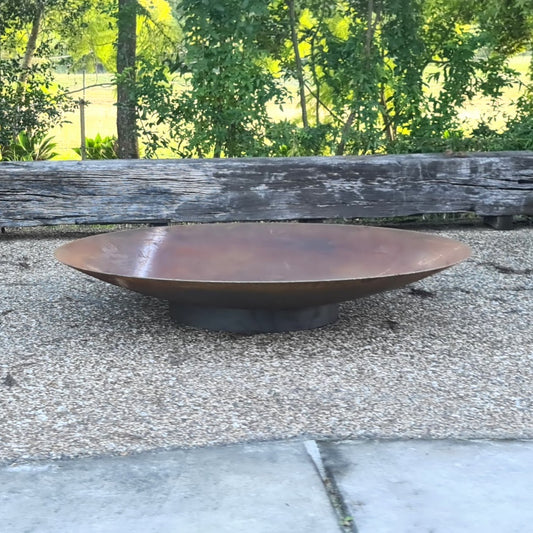 A Corten steel fire pit with timber surround to sit